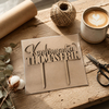 Personlig kaketopp i tre i emballasje på et verksted, klar til sending ved siden av jutesnøre, saks og en kaffekopp